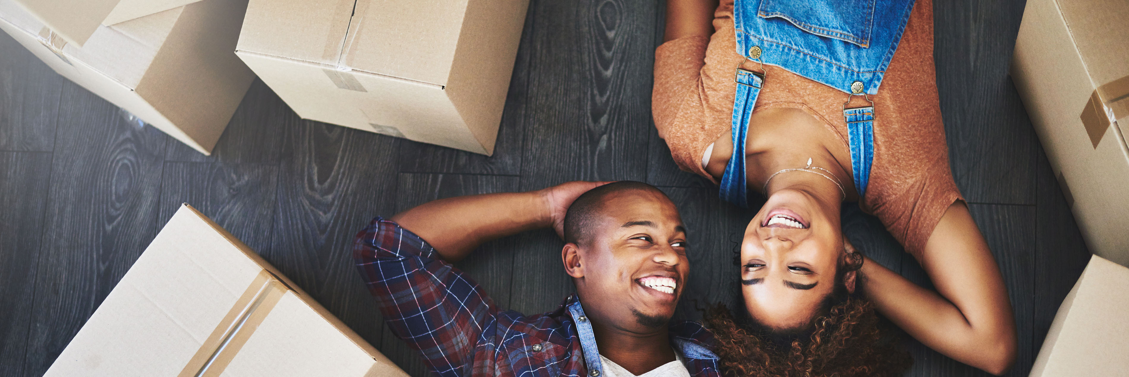 Couple lying on floor surrounded by moving boxes