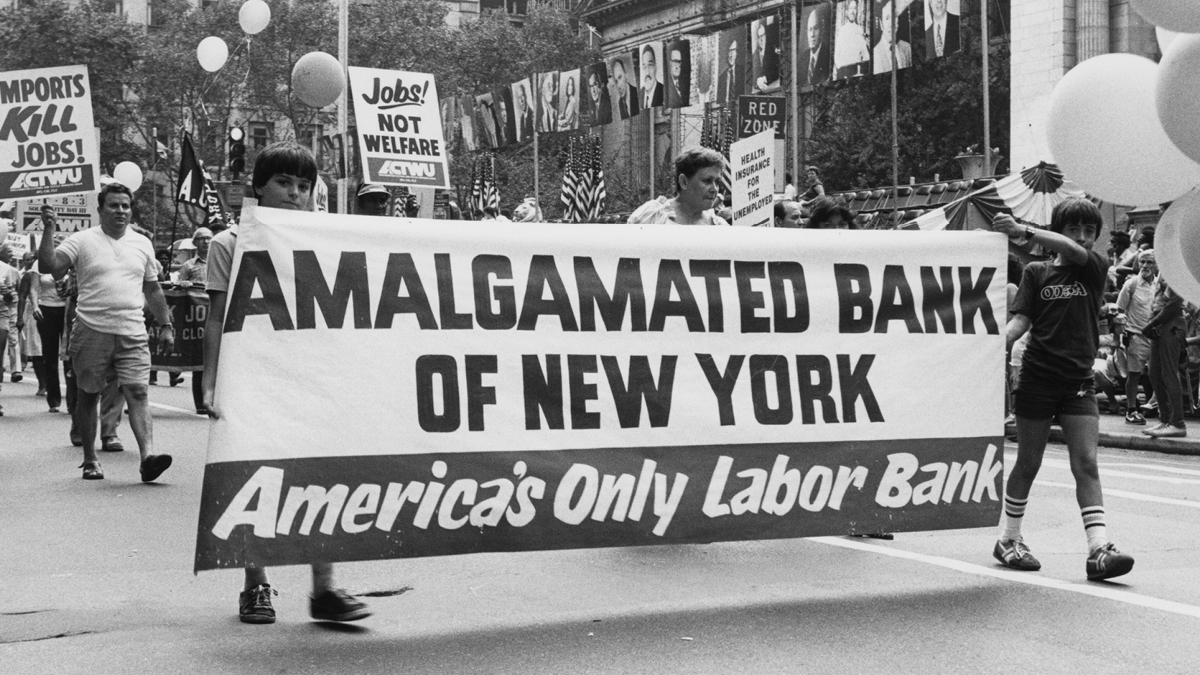 People walking in a parade holding an Amalgamated Bank of New York banner