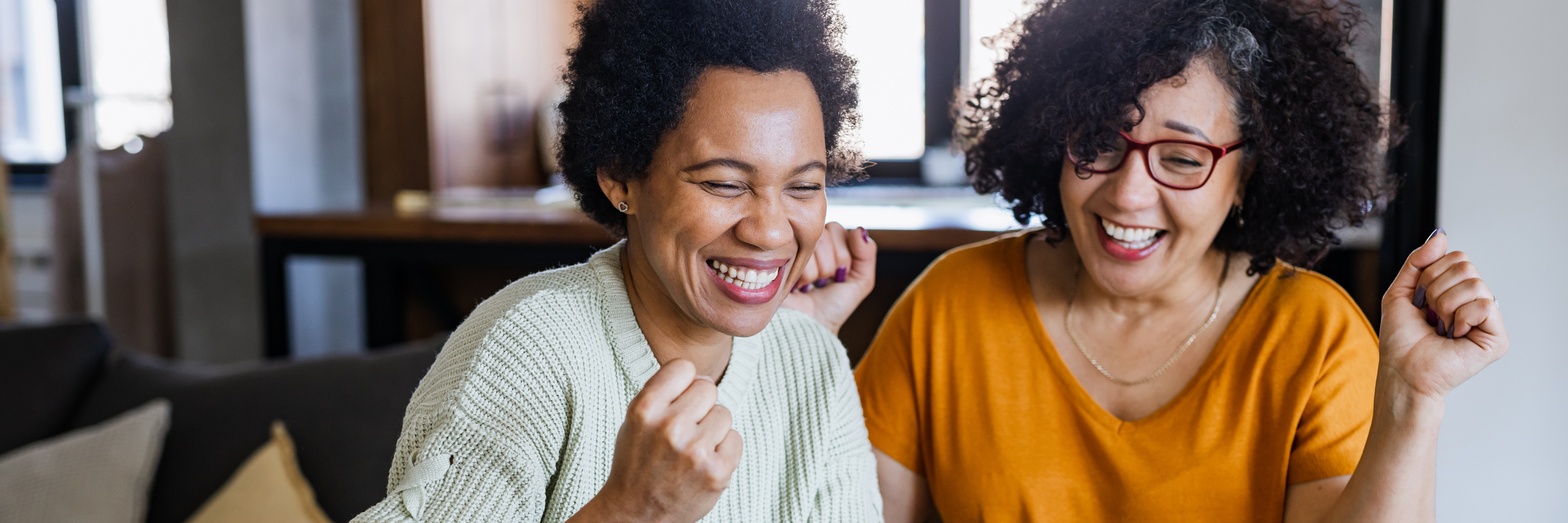 Two women smiling and working at a desk together