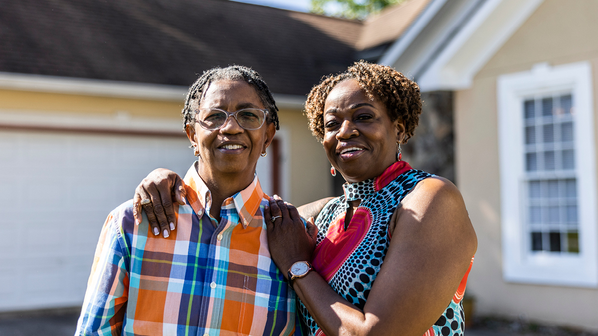 Two people standing in front of a house