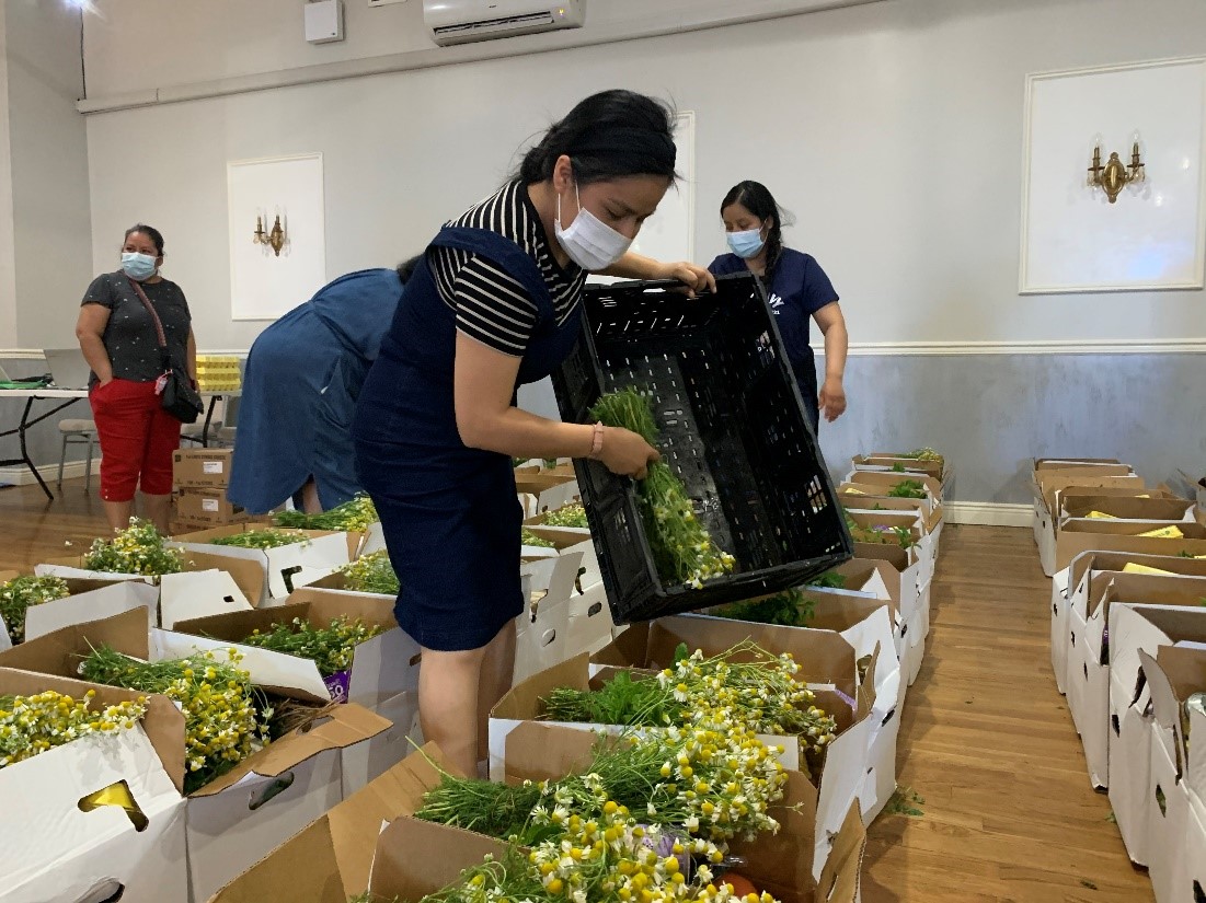 Woman with facemask on putting flowers into a box